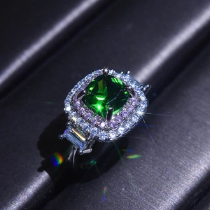 Macro detail of square emerald-cut green gemstone ring with double halo diamond pave