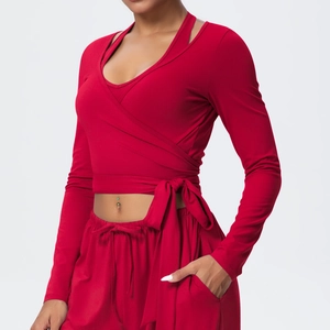 Detail of red long-sleeve yoga top featuring cross-wrap design and side bow tie closure