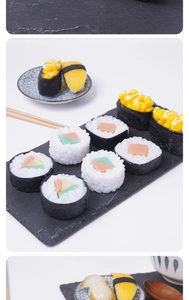 Macro shot of realistic PVC sushi models on a slate board with Japanese chopsticks