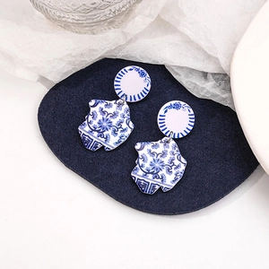 Macro detail of blue and white porcelain pattern on geometric acrylic drop earrings