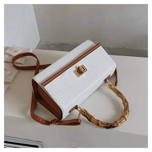 Top view of white croc-embossed handbag with brown strap and natural bamboo handle