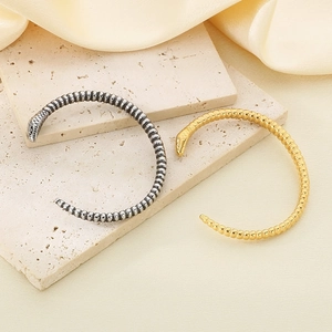Close-up of vintage punk snake head bracelet showing detailed scale texture on silk background