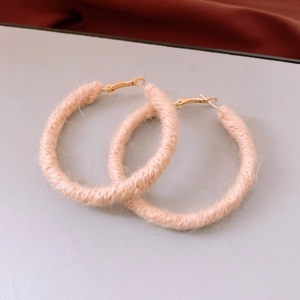 Detailed view of pink wool-wrapped hoop earrings with elegant gold metal clasps