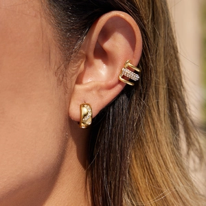 Orecchini a cerchio in acciaio dorato e ear cuff con strass bianchi indossati sul modello