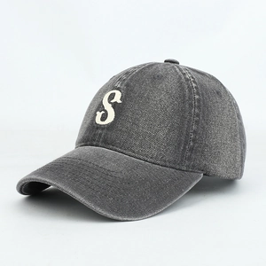 Detailed close-up of gray washed denim baseball cap with white towel-stitched S embroidery