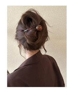 Détail d'une pince à cheveux en résine ambre tenant un chignon élégant sur un modèle