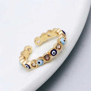 Close-up of golden open ring with blue evil eye enamel and zircon pavé on white tray