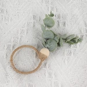 Rustic eucalyptus leaf napkin ring with natural twine and wooden bead on white fabric