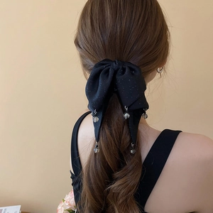 Detail of a black sparkling bow hair claw with transparent beads worn by a model