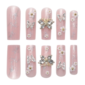 Extra long pink coffin nails with glitter silver glitter, white flowers and rhinestone butterfly