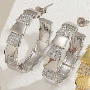 Macro view of C-shaped snake scale earrings with pave-set cubic zirconia stones