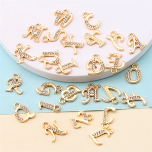 Close-up of gold alloy alphabet pendants with rhinestones on colorful backgrounds