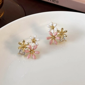 Detail of floral earrings featuring enamel daisies and zircon stones on a ceramic tray