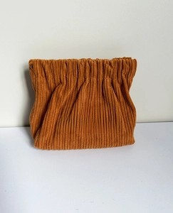 Detail of orange corduroy storage bag showing textured fabric and Free Travel patch