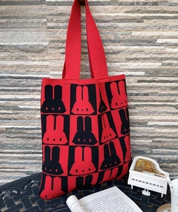 Close-up of red and black knitted tote bag featuring cartoon bunny jacquard patterns