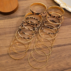 Macro detail of 20-piece vintage gold and leopard print bangle set on wooden background