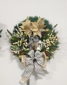 Detail of Christmas wreath with Holy Family motif, golden poinsettia, and LED lantern