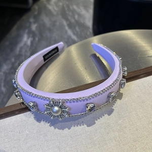 Close-up of purple padded headband with rhinestone chains and handmade pearl flower detail