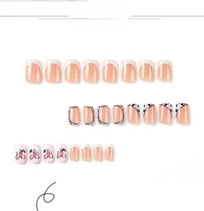 Detail view of pink and white French press-on nails with black hearts and glitter accents
