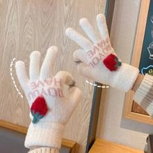 Detail of child white knitted glove with red strawberry decor and pink letter embroidery