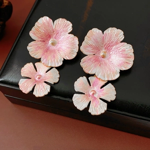 Macro detail of pink and white enamel flower earrings on a black leather gift box surface