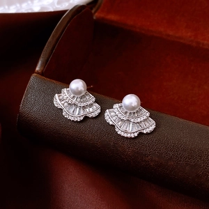 Close-up of fan-shaped silver earrings with micro-pave zircons and pearls on satin