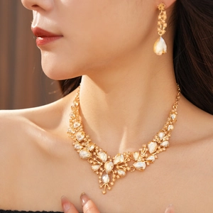 Close-up of champagne crystal V-shaped necklace and drop earring set on model neck