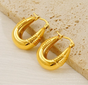 Macro shot of 18K gold plated U-shaped earrings with intricate cross-hatch texture detail