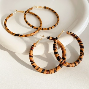 Détail de créoles bohèmes avec cuir tressé marron et crochets en métal doré
