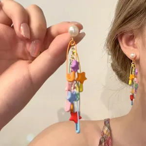 Detailed shot of long paperclip earrings with colorful stars and pearl stud elements