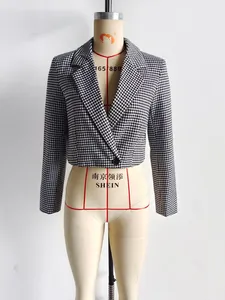 Détail de la veste courte à motif pied-de-poule noir et blanc avec bouton unique