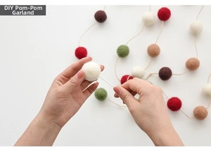 Macro shot of hands threading colorful felt wool balls for DIY Christmas garland decor