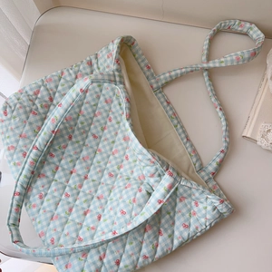 Macro view of blue gingham quilted tote bag with pink floral and red bow patterns