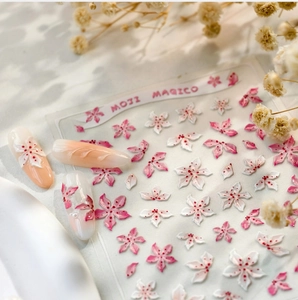 Detail of 3D pink sakura nail stickers with gradient base and pearl accents
