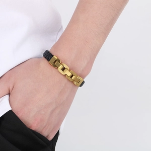 Detail of man wearing black braided leather bracelet with polished gold metal chain clasp