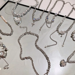 Detailed flat lay of silver necklaces with heart pendants and star charms on mirror