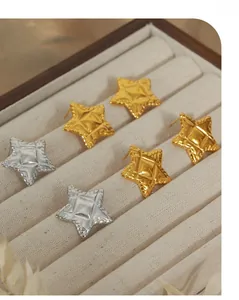 Détail de boucles d'oreilles en étoile avec texture matelassée en plaqué or et argent