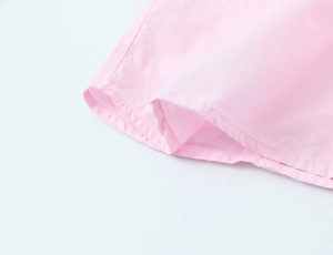 Close-up of double-stitched hem on pink poplin fabric showing texture and detail