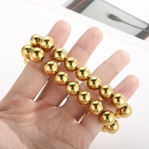 Close-up of dual stacked golden beaded bracelets featuring polished metallic round beads