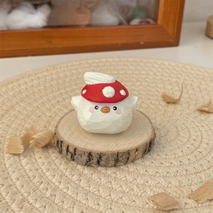 Handcrafted wooden bird figurine wearing a red mushroom hat on a natural wood base