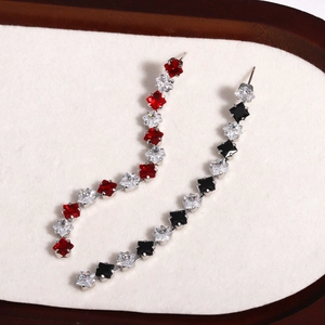 Macro shot of silver tassel earrings featuring red, black, and clear square-cut zircons