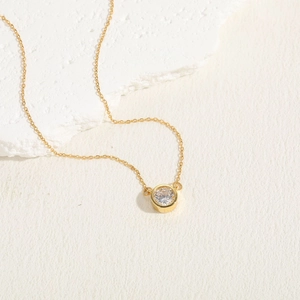 Detailed close-up of a gold choker necklace featuring a bezel-set round zircon pendant