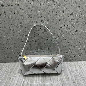 Close-up of silver woven leather handbag with gold triangle hardware and zipper detail