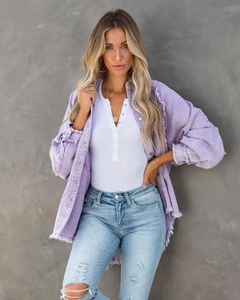 Detail der lila Jeansjacke mit ausgefransten Kanten und metallischen Knöpfen am Ärmel