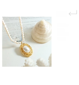 Detail of freshwater pearl necklace with gold-plated textured oval pendant on vintage books
