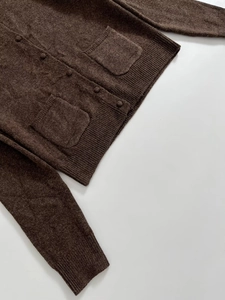 Detailed view of dark brown knit cardigan featuring button closure and ribbed textures