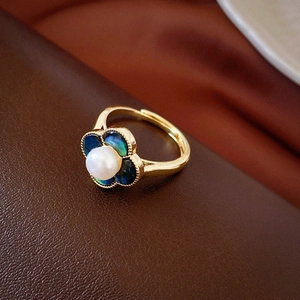 Detail eines Schmetterlingsrings mit Perle und schimmernden Blüten auf Goldband