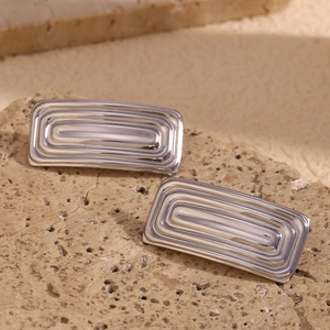 Detailed macro view of silver polished metal stud earrings on a natural stone surface
