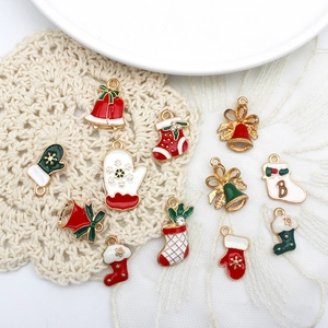 Detail of colorful enamel Christmas charms including Santa gloves and bells on lace mat