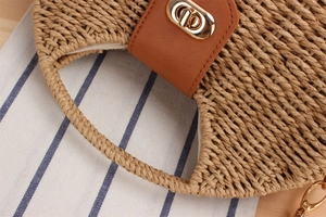 Detail of woven paper straw texture and gold metal twist lock on a beige crossbody bag